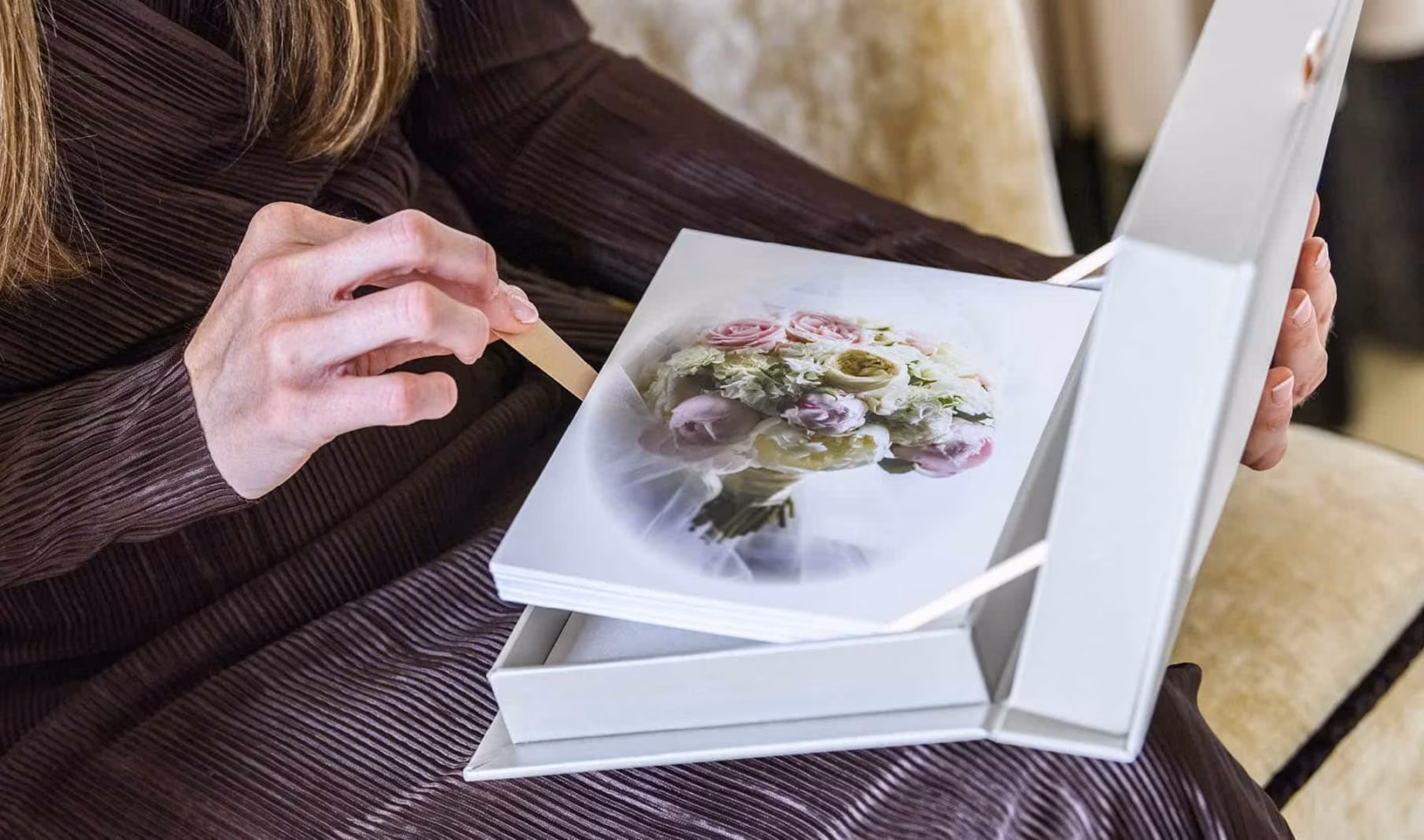 Bride holding a wedding photo book open to a bouquet photograph