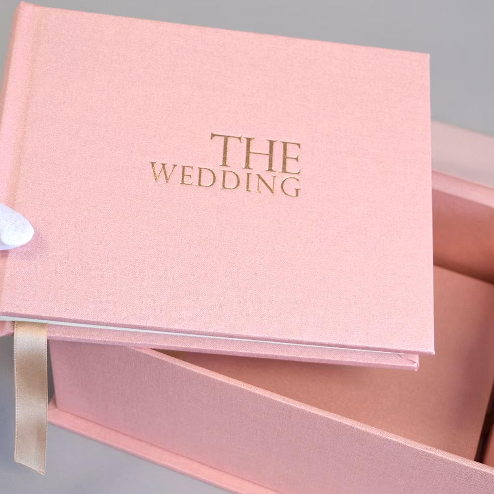 Pink wedding album with a gold-foiled title displayed in its matching presentation box