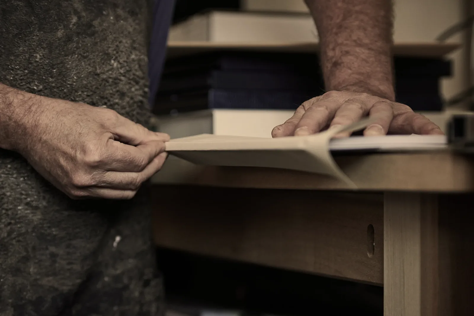 Bookbinder hand-finishing a bespoke book at the workbench