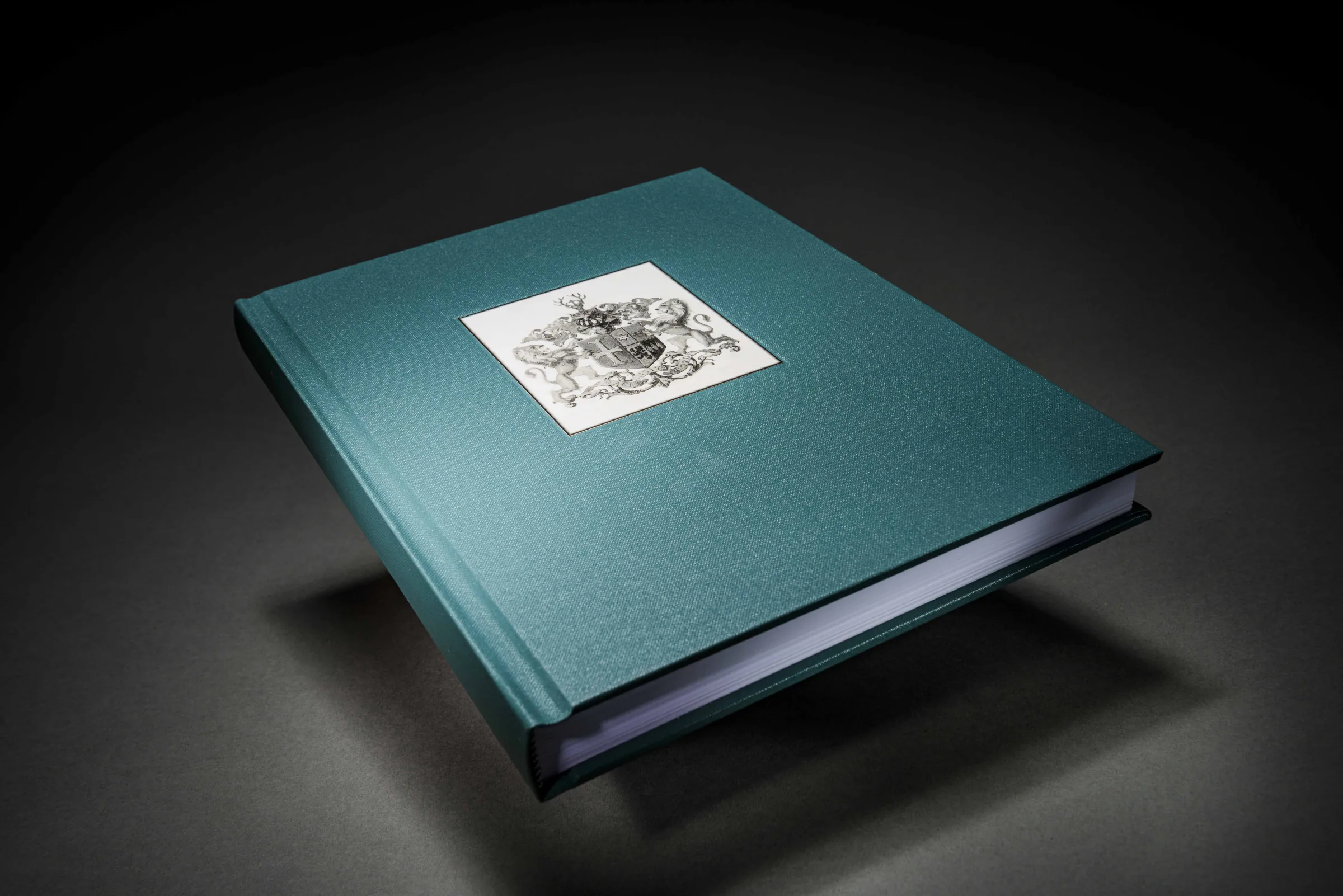 Green cloth-bound family history photo book with an inset crest