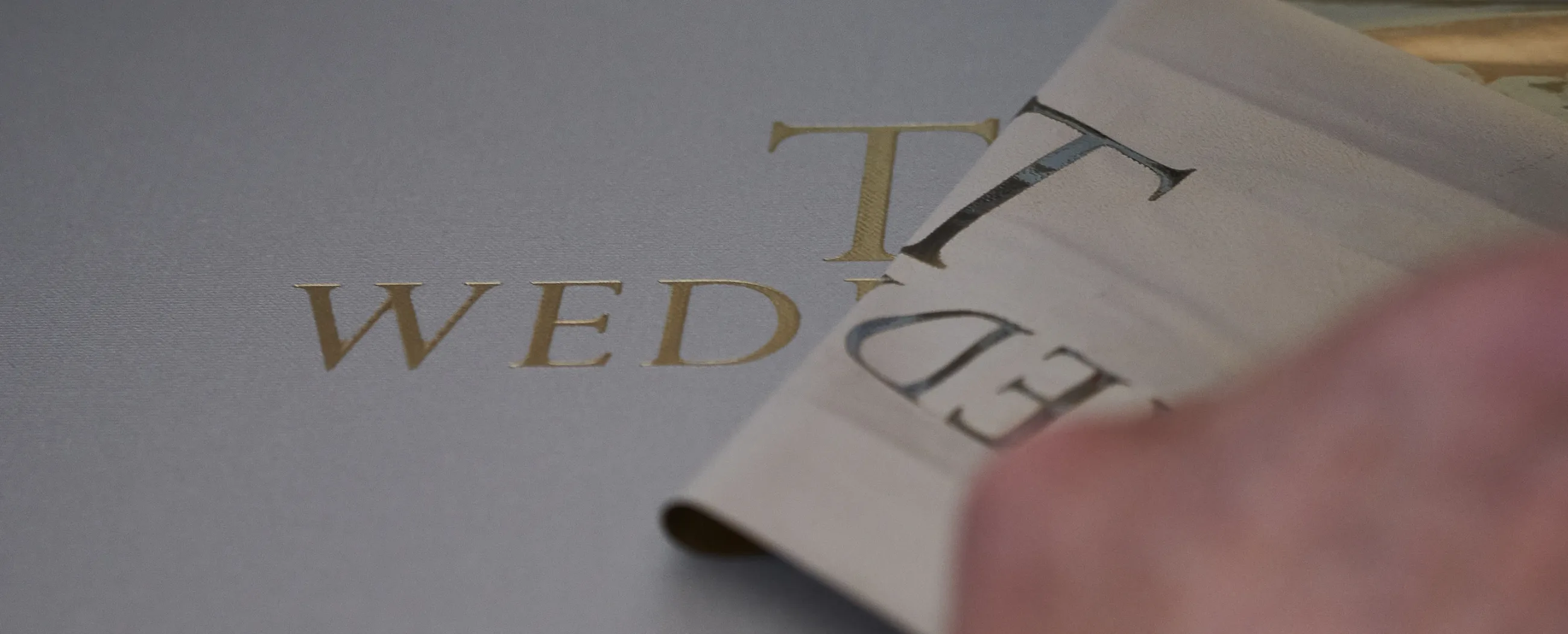 Bookbinder lifting a freshly foiled sheet at the workbench
