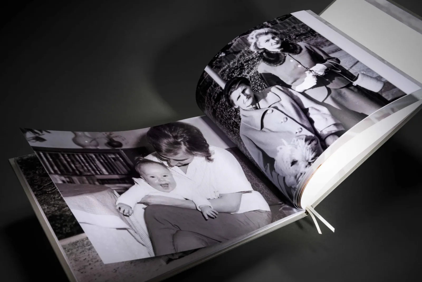 Open family history photo book displaying black-and-white family photographs