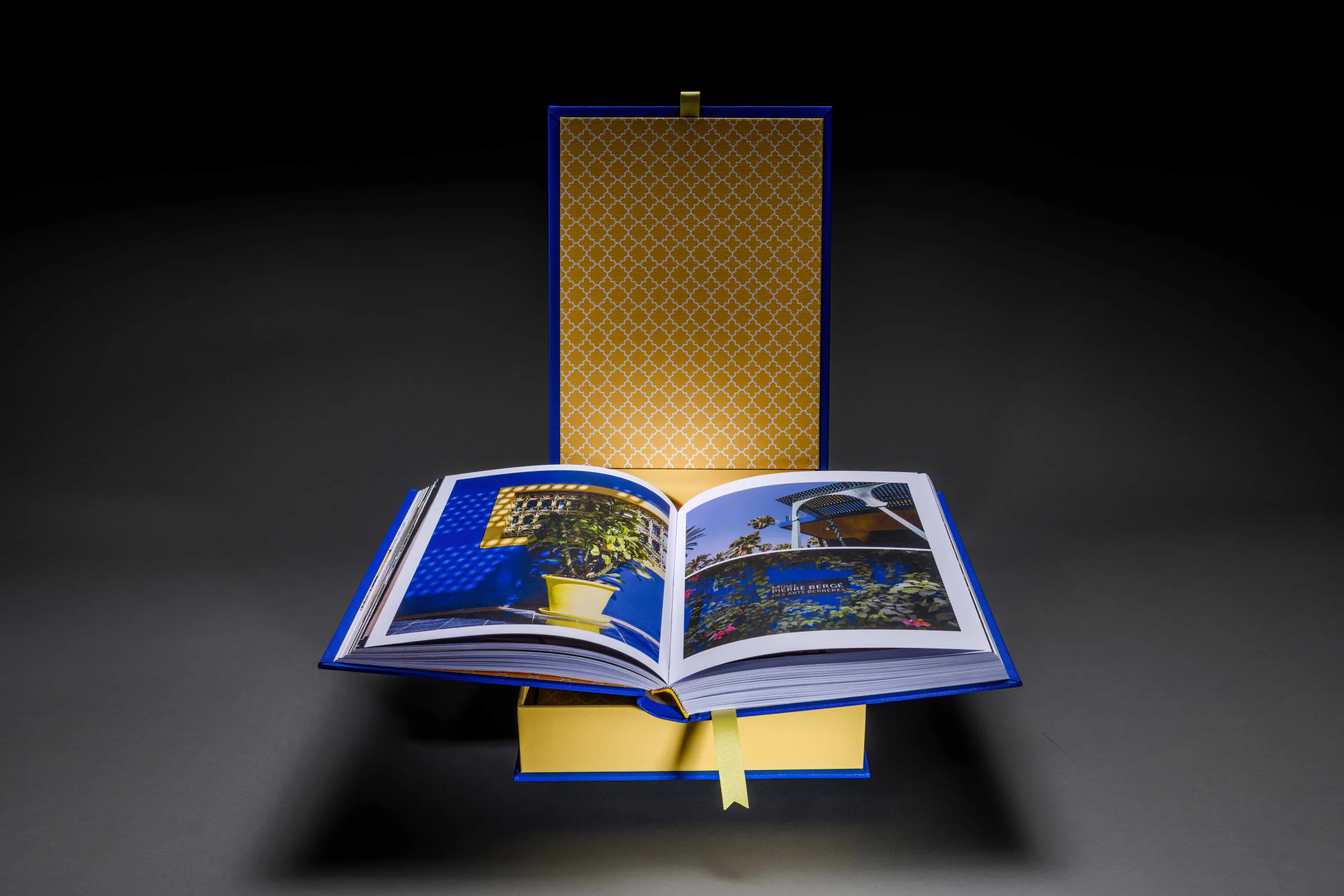 Open travel photo book showing Marrakech photographs in a blue and gold presentation box