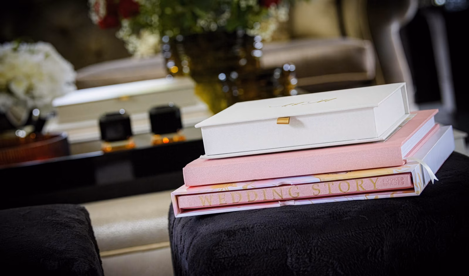 White and pink wedding albums stacked on a sofa