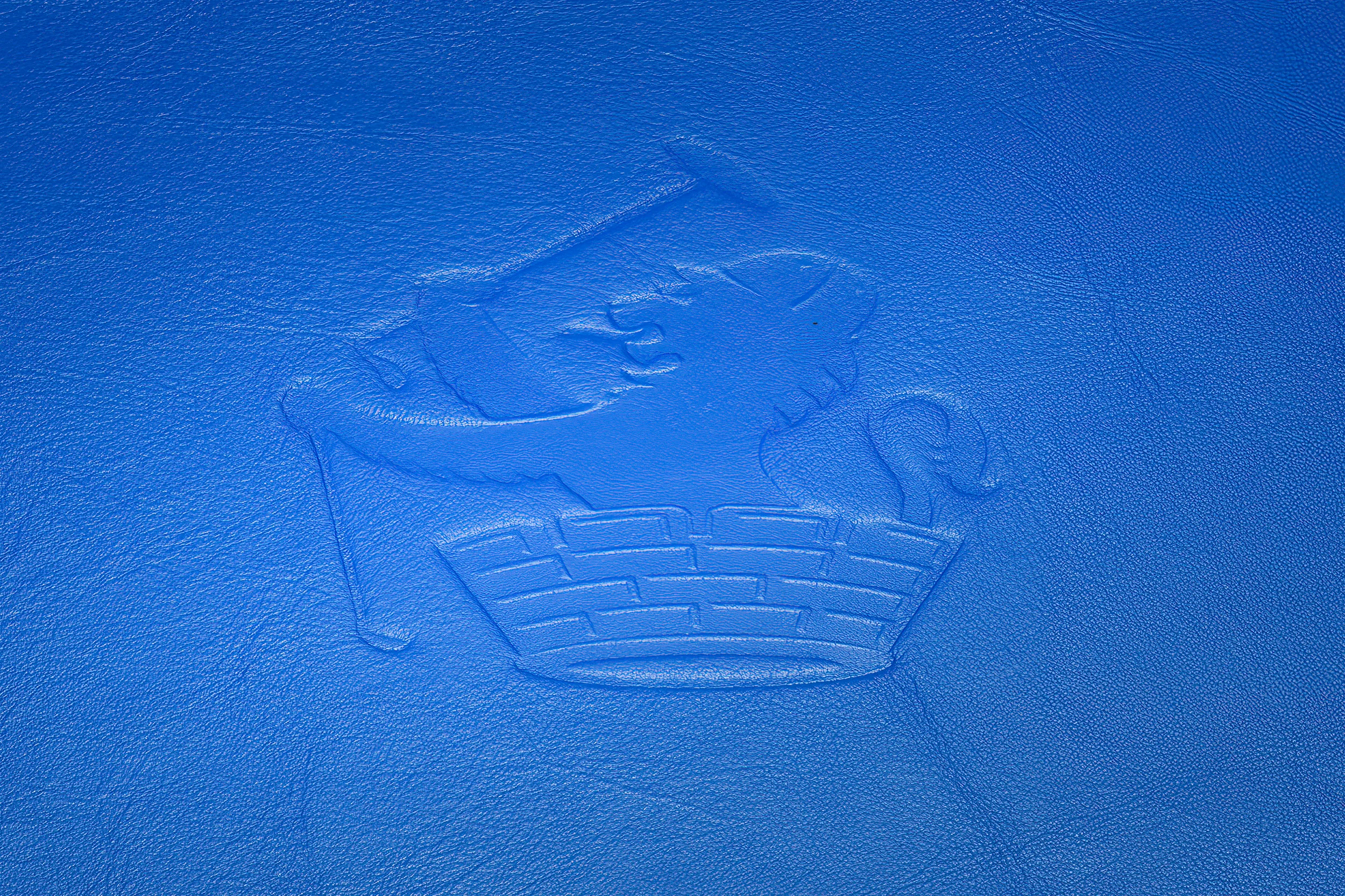 Close-up of a debossed circular mark on blue leather