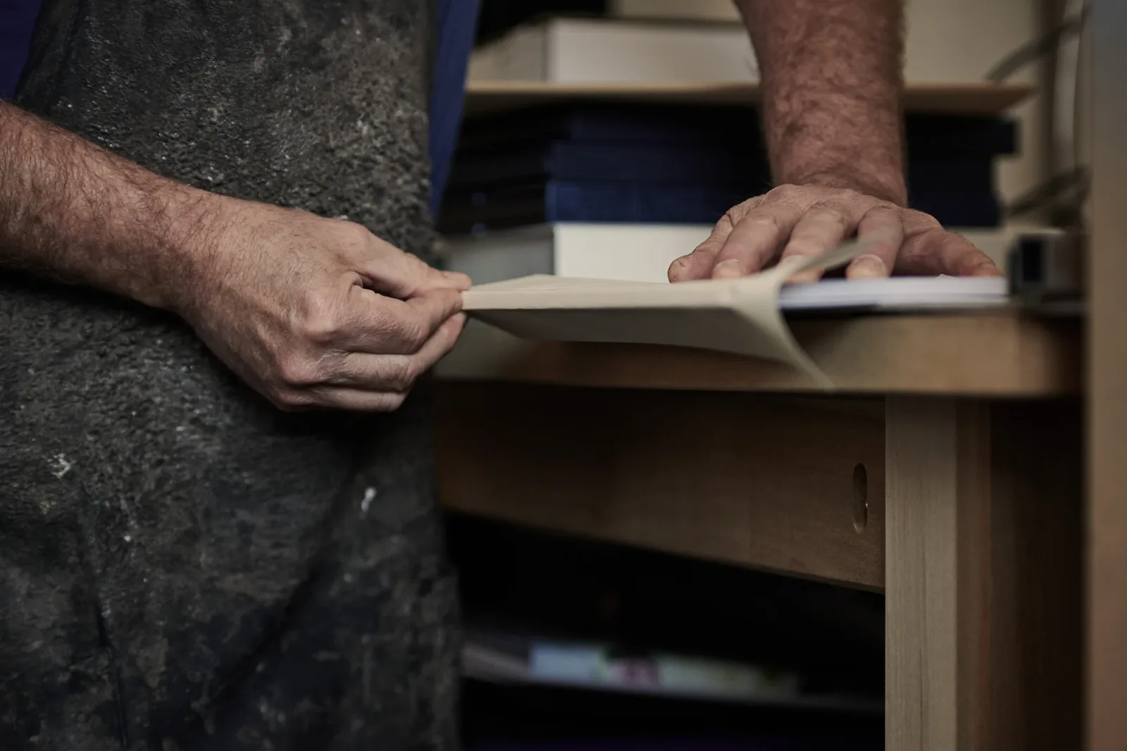 Hands hand-binding a bespoke photo book at the Booked Images workbench