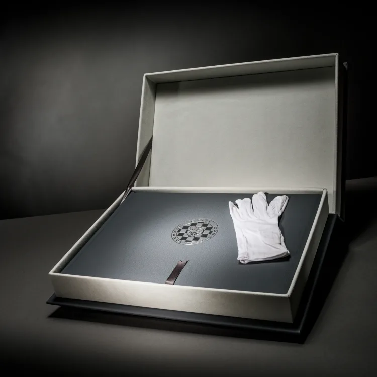 Black Porsche book displayed in its presentation box with white archival handling gloves