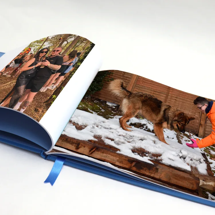 Blue family photo book opened to a spread of treasured dog photographs