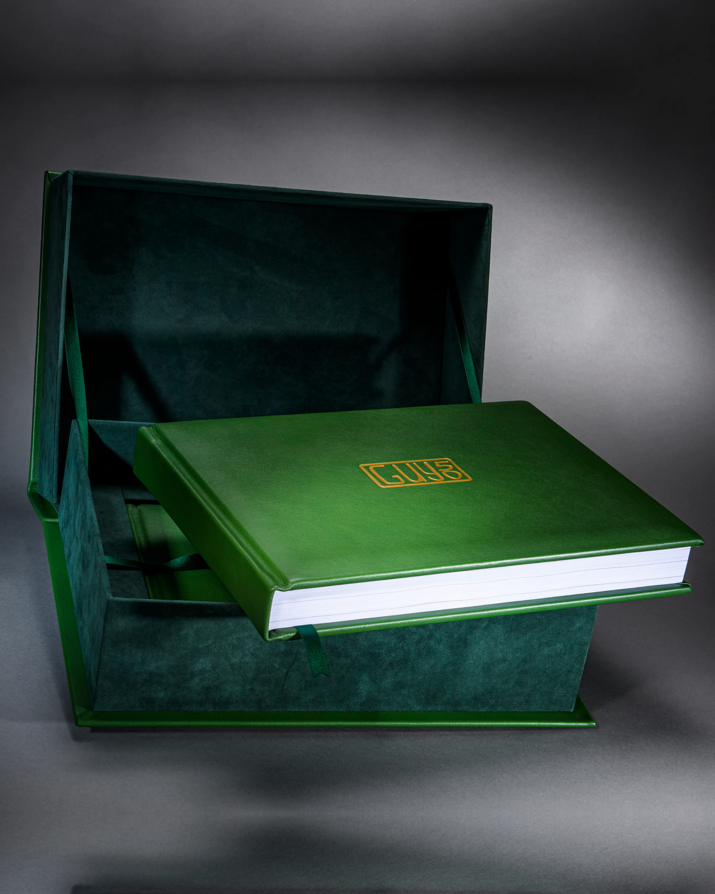 Green leather GUS 50 celebration book displayed inside a matching velvet-lined presentation box