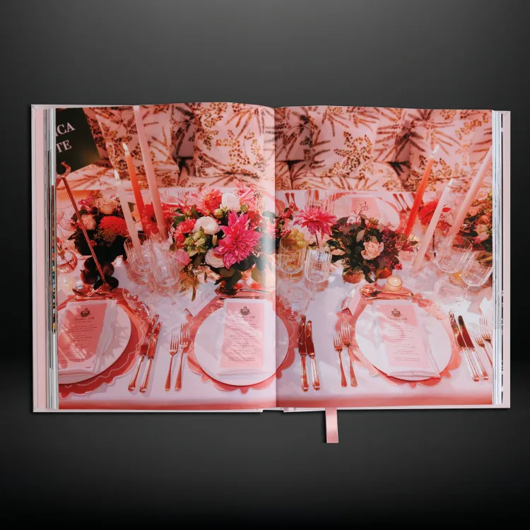 Celebration book opened to photographs of pink floral event tables