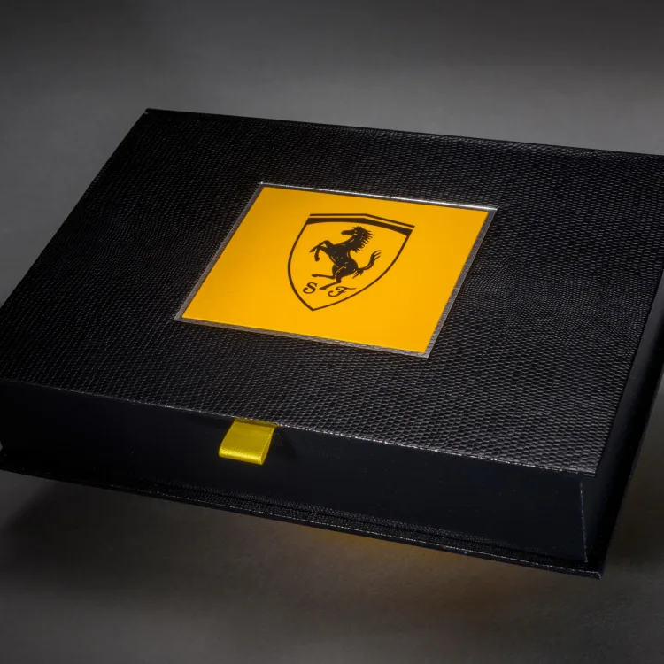 Black Ferrari presentation box finished with a yellow marque inlay and ribbon pull