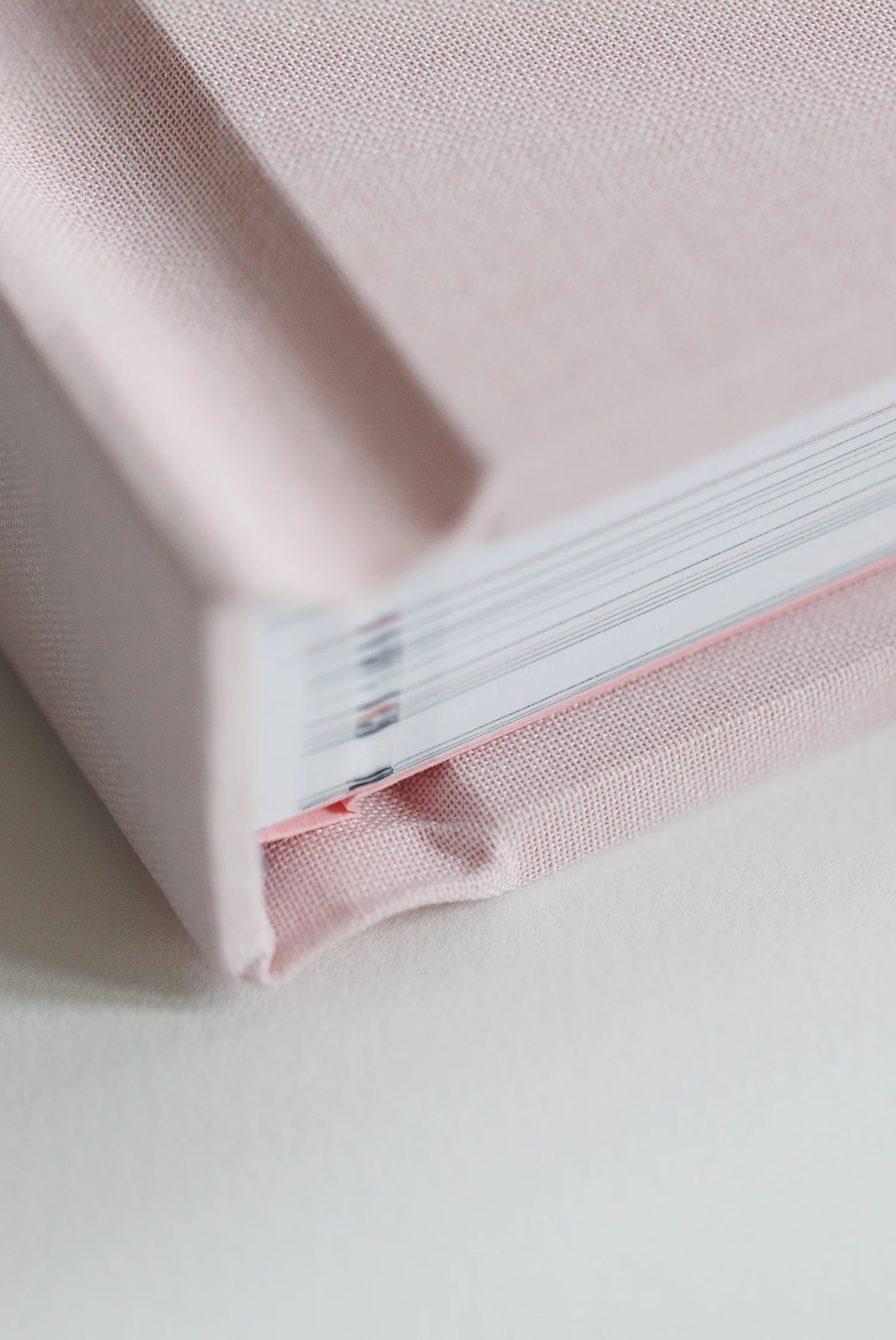 Close detail of a pink hand-bound book with ribbon and stitched pages