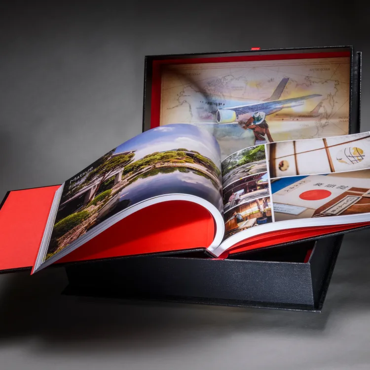 Travel photo book opened to landscape photographs in a red-lined map presentation box