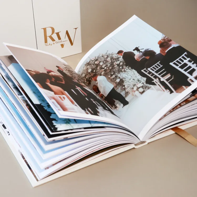 Wedding photo album opened to a ceremony spread with its presentation box behind