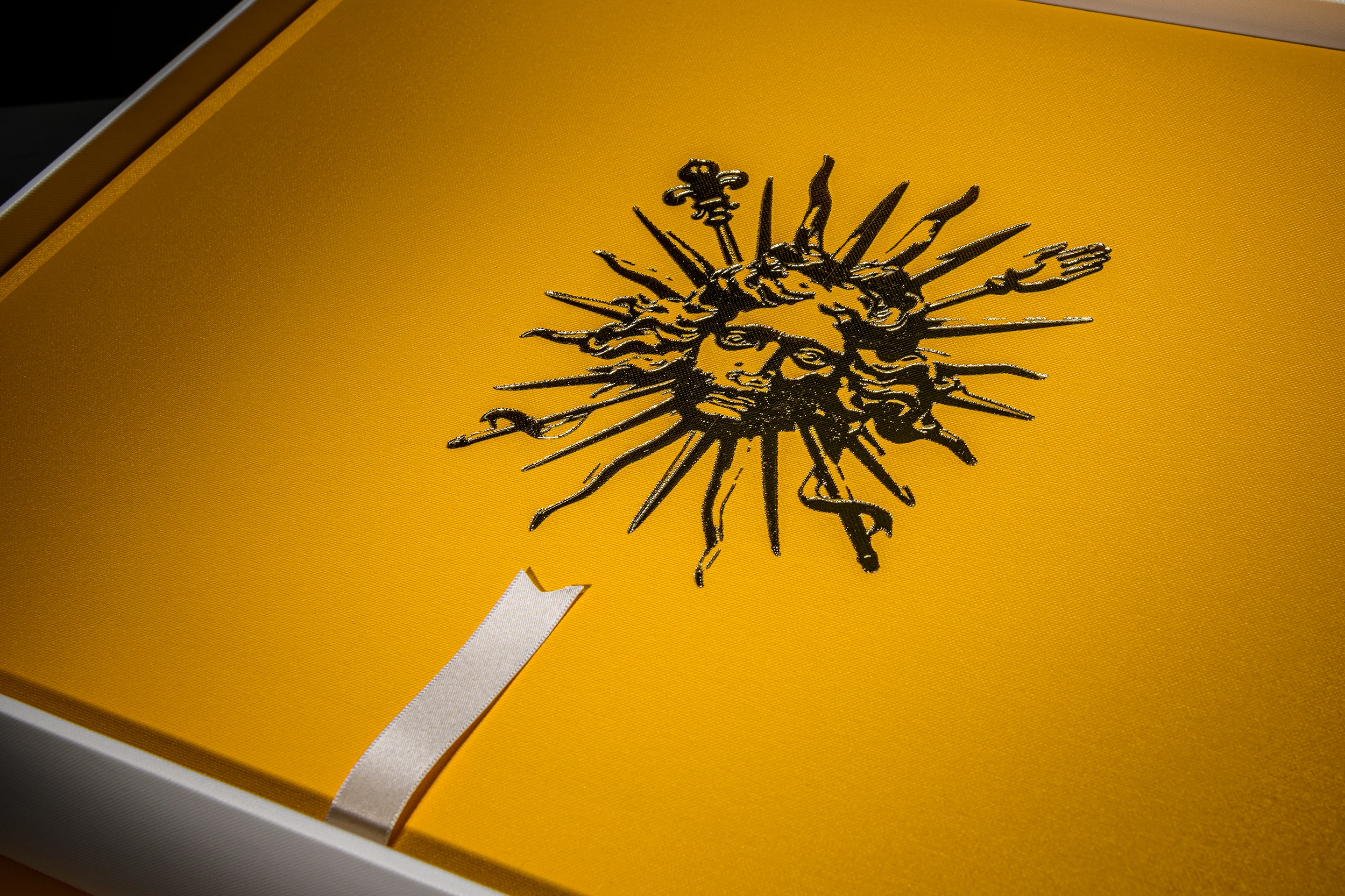 Close-up of a yellow heritage buckram photo book with a black decorative motif and white ribbon