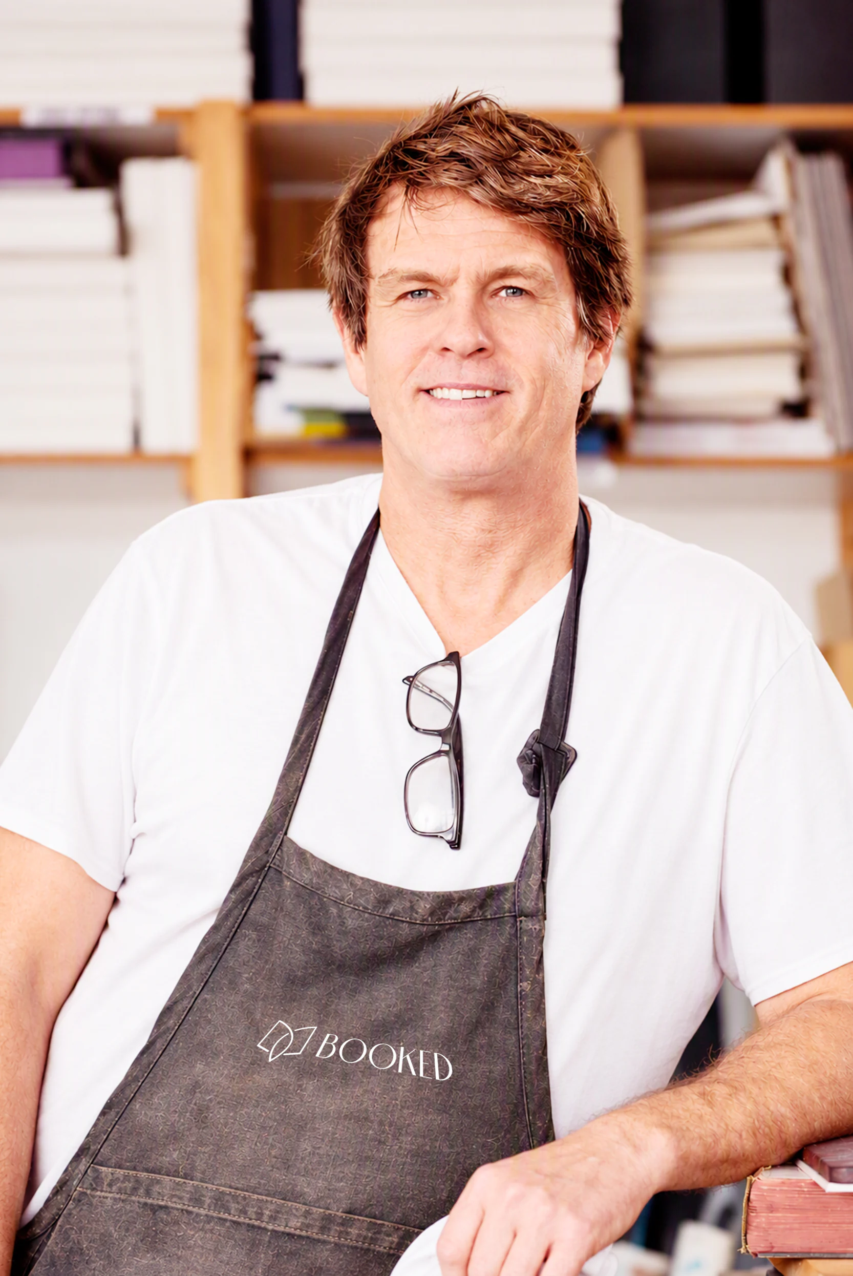Frank, Master Bookbinder at Booked Images, wearing a branded apron in the bindery
