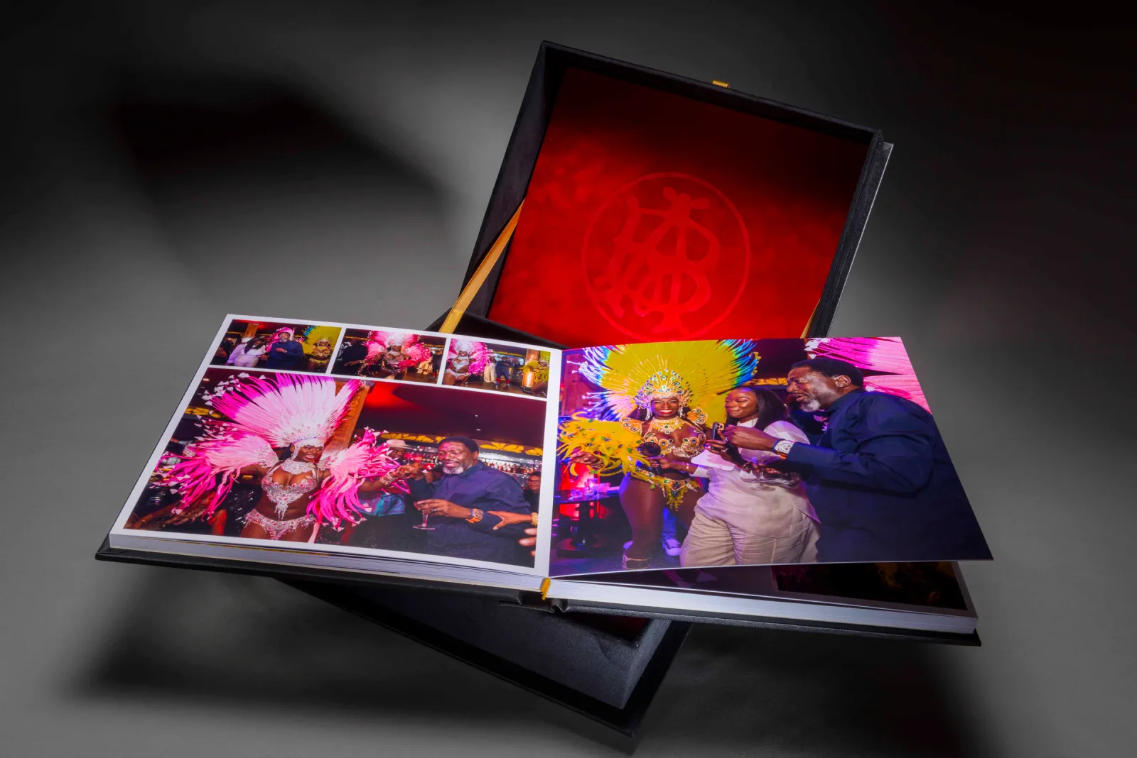 Open celebration photo book with colourful party photographs inside a red-lined presentation box